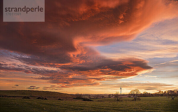 Spektakulärer  leuchtender Sonnenuntergang mit linsenförmigen Wolken am Himmel; Shaftoe Crags  Northumberland  England