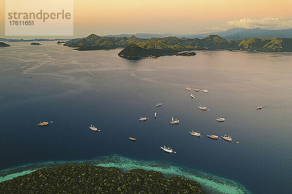 Luftaufnahme von Booten  die an der Küste einer Insel im Komodo-Nationalpark  der Heimat des berühmten Komodowarans  vertäut sind; Ost-Nusa Tenggara  Kleine Sunda-Inseln  Indonesien