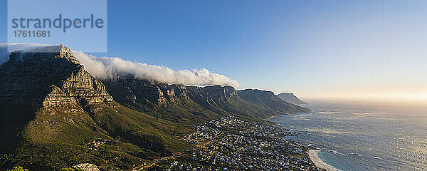 Wolkenformation mit Tischtuch-Effekt über der Bergkette der Zwölf Apostel mit Blick auf die Skyline von Kapstadt und die Camps Bay an der Atlantikküste; Kapstadt  Provinz Westkap  Südafrika