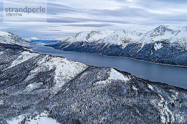 Luftaufnahme des Tutshi-Sees an einem grauen Tag mit dramatischen Wolken und schneebedeckten Bergen im Winter; Yukon  Kanada