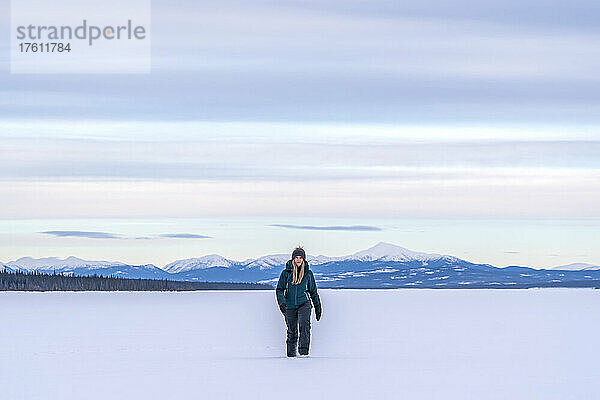 Frau im Schnee  während sie auf dem zugefrorenen Tagish Lake auf die Kamera zugeht; Tagish  Yukon  Kanada
