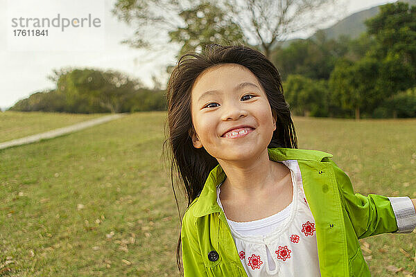 Junges Mädchen läuft mit einem breiten Lächeln auf die Kamera zu; Hongkong  China
