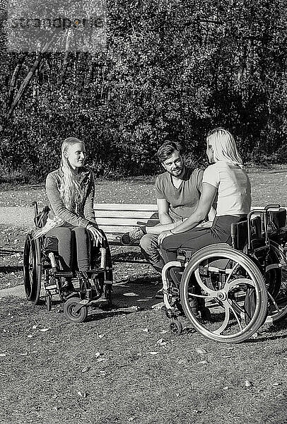 Schwarz-Weiß-Bild einer Gruppe von drei jungen Querschnittsgelähmten in ihren Rollstühlen  die an einem schönen sonnigen Tag gemeinsam einen Park besuchen; Edmonton  Alberta  Kanada