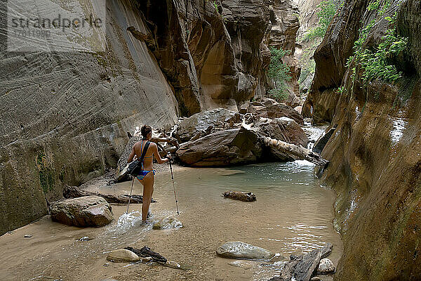 Eine junge Frau erkundet den Oberlauf von The Narrows im Zion-Nationalpark.