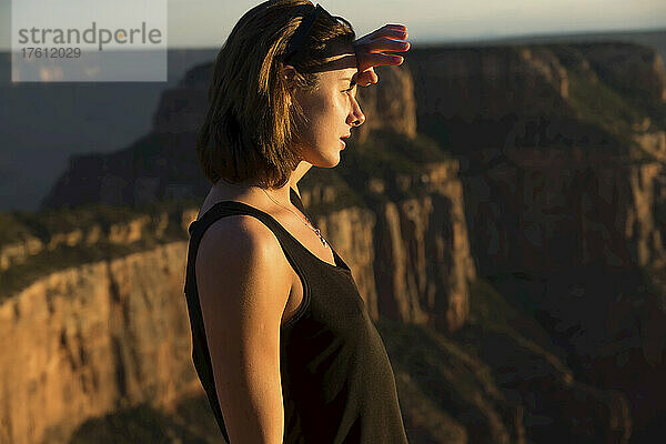 Eine junge Frau bewundert die Landschaft des Grand Canyon bei Sonnenuntergang.