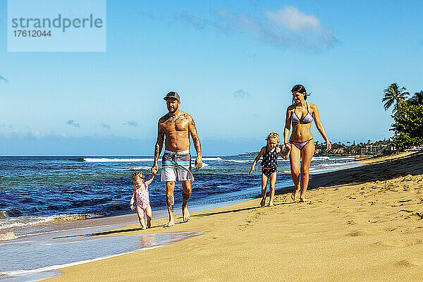 Eine Familie mit zwei kleinen Töchtern  die gemeinsam am Ka'anapali Beach spazieren gehen; Ka'anapali  Maui  Hawaii  Vereinigte Staaten von Amerika