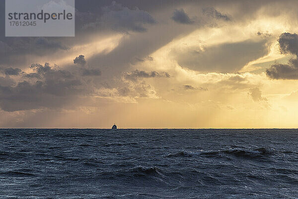 Ein Schiff segelt nach einem Sturm auf See über den Horizont in den Sonnenuntergang; Brighton  East Sussex  England