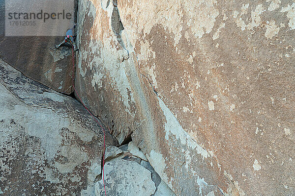 Ein Felskletterer arbeitet sich an einer technischen Granitwand hoch.