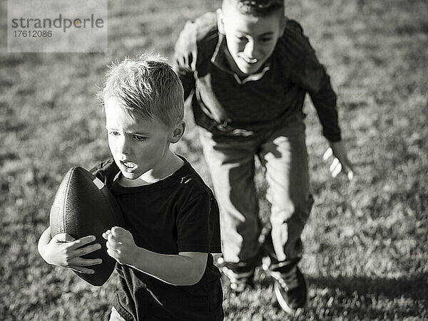 Zwei Brüder rennen mit einem Fußball über den Rasen; St. Albert  Alberta  Kanada