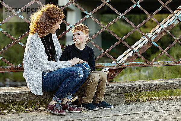 Mutter und Sohn sitzen zusammen und unterhalten sich auf einer Brücke in einem Park; Edmonton  Alberta  Kanada