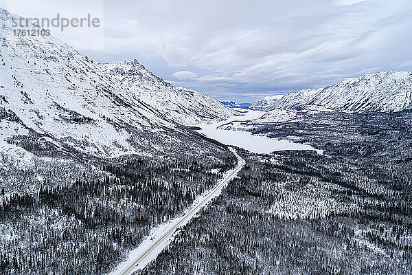 Der South Klondike Highway schlängelt sich unter bewölktem Himmel durch die winterliche Yukon-Landschaft; Carcross  Yukon  Kanada