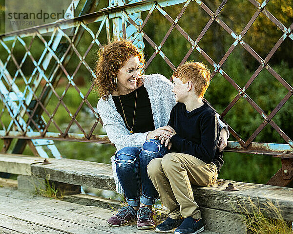 Mutter und Sohn sitzen zusammen und unterhalten sich auf einer Brücke in einem Park; Edmonton  Alberta  Kanada