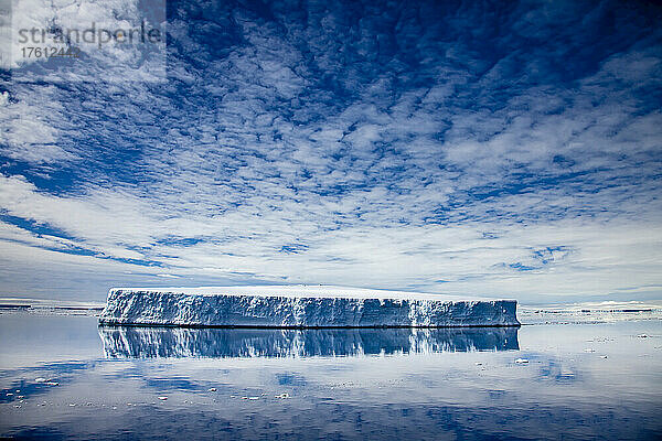 Ein tafelförmiger Eisberg spiegelt sich im ruhigen Wasser.