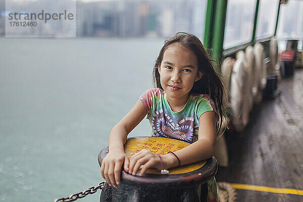 Junges Mädchen  das auf der Star Ferry steht und während einer Überfahrt über den Victoria Harbour zwischen Hongkong Island und Kowloon hinausschaut; Hongkong  China