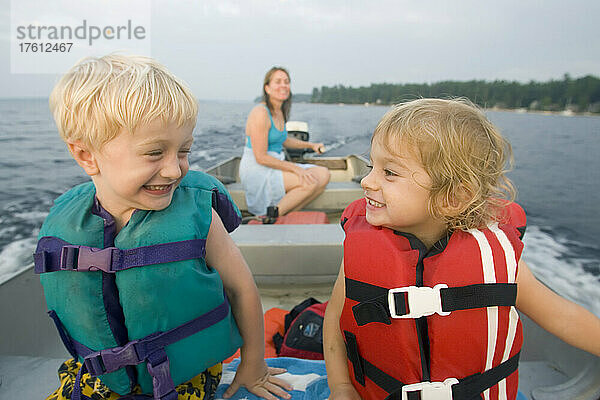 Zwei Kinder lächeln sich in einem Außenbordmotorboot zu; Sebago Lake  Maine