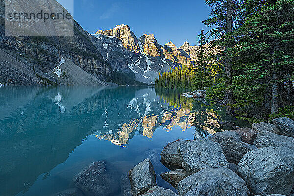 Das Tal der Zehn Zinnen spiegelt sich im ruhigen Wasser des Moraine Lake unter einem strahlend blauen Himmel im Banff National Park; Alberta  Kanada