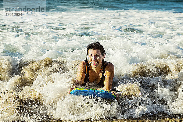 Nahaufnahme einer Frau  die auf einem Bodyboard eine Welle ins Ufer reitet  am D. T. Fleming Beach; Kapalua  Maui  Hawaii  Vereinigte Staaten von Amerika