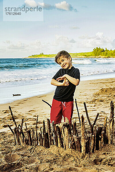 Ein kleiner Junge steht am Strand und zeigt stolz seine Kreation im Sand am D. T. Fleming Beach; Kapalua  Maui  Hawaii  Vereinigte Staaten von Amerika