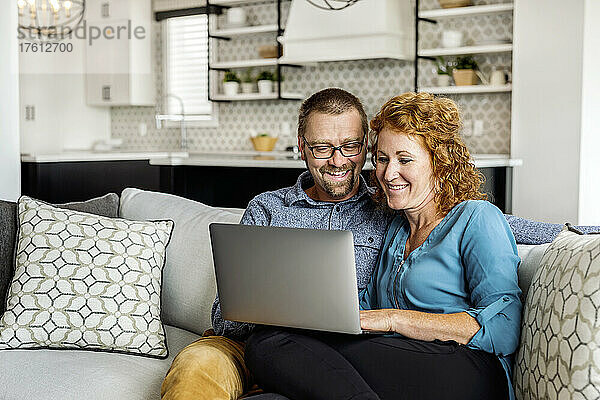 Ehepaar sitzt zu Hause auf einer Couch und benutzt seinen Laptop; Edmonton  Alberta  Kanada