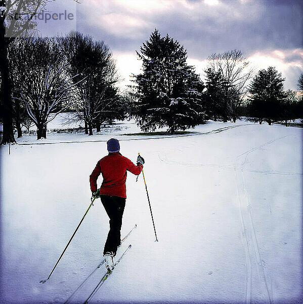 Eine Frau fährt während eines frühen Winterschneefalls Langlauf auf einem Golfplatz; Montgomery Country  Maryland.
