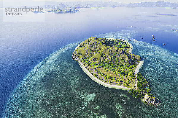 Luftaufnahme von Booten  die vor einer Insel im Komodo-Nationalpark vertäut sind  mit einem Dock  das in das umgebende türkisfarbene Wasser hineinragt; Ost-Nusa Tenggara  Kleine Sunda-Inseln  Indonesien