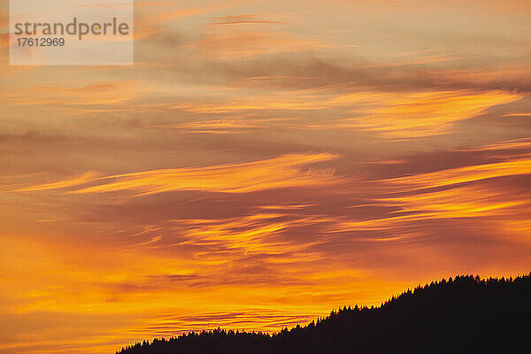 Goldene Sonnenuntergangswolken am Himmel über einer silhouettierten Landschaft; Bayern  Deutschland