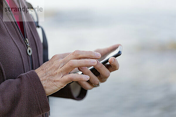 Nahaufnahme der Hände einer Frau  die beim Wandern ein Smartphone benutzt; British Columbia  Kanada