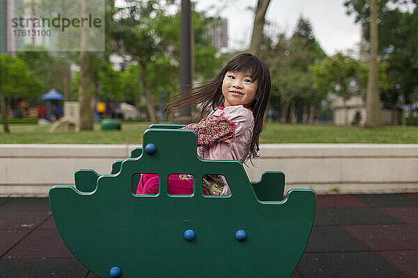 Junges Mädchen spielt auf einem bunten Spielplatz und schaut in die Kamera; Hongkong  China