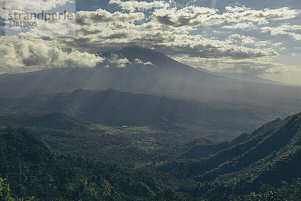 Sonnenlicht  das durch die Wolken auf ein Tal und die darunter liegende Berglandschaft fällt  gesehen von Lahangan Sweet; Kabupaten Karangasem  Bali  Indonesien