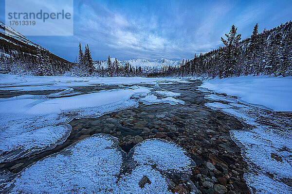 Schneebedeckte Eisformationen auf dem Wheaton River mit den schneebedeckten Bergen in der Ferne im Winter; Whitehorse  Yukon  Kanada