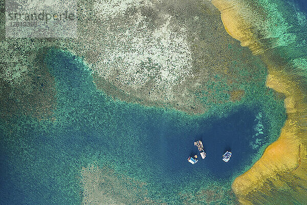 Blick von oben auf Boote  die in einer vorgelagerten Lagune im Komodo-Nationalpark mit einer Sandbank und türkisfarbenem Küstenwasser vor Anker liegen; Ost-Nusa Tenggara  Kleine Sunda-Inseln  Indonesien