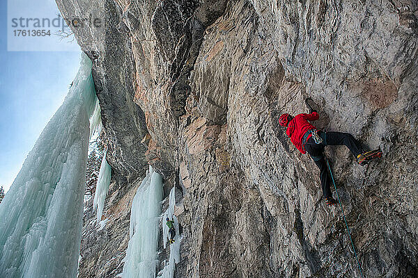 Ein Kletterer klettert mit Eispickel und Steigeisen eine Felswand im East Vail Amphitheater in Colorado hoch.
