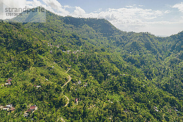 Überblick über den Berghang mit Häusern auf dem Berg Abang  mit blauem  bewölktem Himmel und üppiger Vegetation; Abang  Kabupaten Karangasem  Bangli Regency  Bali  Indonesien