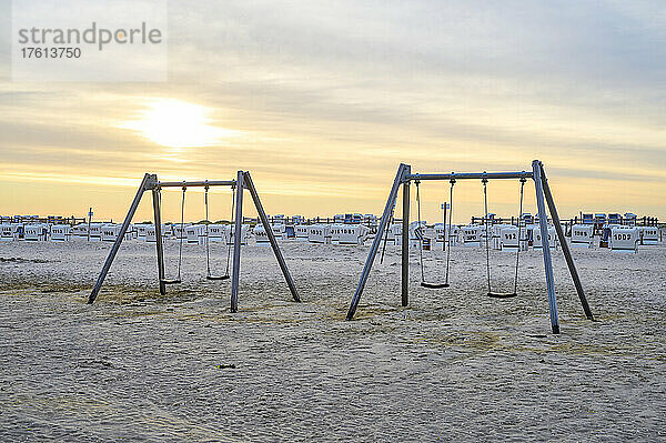 Schaukeln am Sandstrand mit Strandkörben im Hintergrund bei Sonnenaufgang an der Nordsee in einem Seebad in Nordfriesland; Sankt Peter-Ording  Schleswig-Holstein  Deutschland