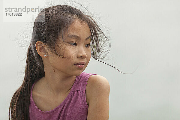 Porträt eines jungen Mädchens mit langen brünetten  vom Wind zerzausten Haaren und einem rosa Hemd; Hongkong  China