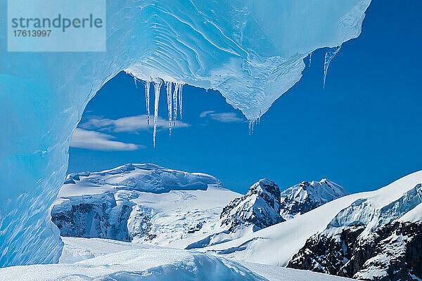 Blick unter einem blauen Eisbogen auf einen Eisberg.