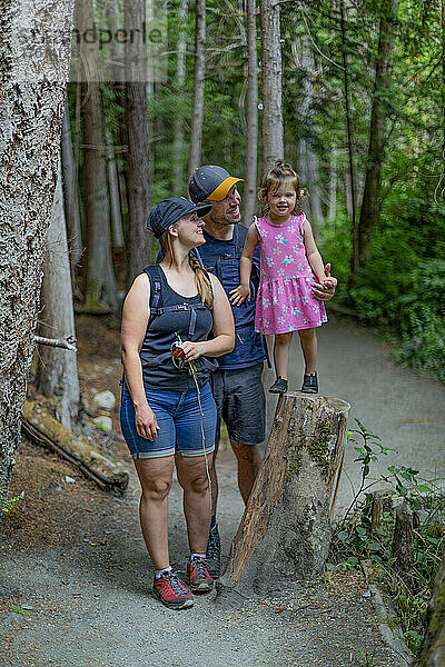 Junge Familie  die sich an den Händen hält und gemeinsam einen Wanderweg im Smuggler Cove Marine Provincial Park an der Sunshine Coast von BC  Kanada  hinuntergeht; British Columbia  Kanada