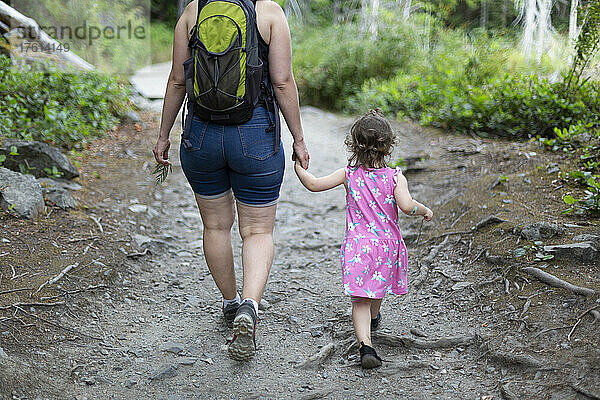 Mutter und kleine Tochter halten sich an den Händen und gehen gemeinsam einen Wanderweg im Smuggler Cove Marine Provincial Park an der Sunshine Coast von BC  Kanada; British Columbia  Kanada