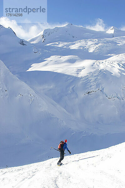 Ein Backcountry-Snowboarder fährt ein Schneefeld in Richtung eines Gletschers hinunter; Selkirk Mountains  British Columbia  Kanada.