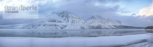 Der schneebedeckte Mount Worthington spiegelt sich in den stillen Wassern des Kathleen Lake wider  wobei neblige  tiefhängende Wolken und blaue Farben eine stimmungsvolle Atmosphäre schaffen; Haines Junction  Yukon  Kanada