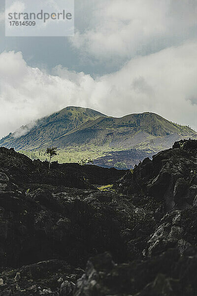 Vulkangestein und Blick auf den Berg Batur (Vulkan Kintamani) im Süden Baturs mit bewölktem Himmel; Kintamani  Bangli Regency  Bali  Indonesien
