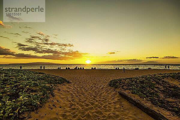 Silhouette von Touristen  die den Strand säumen  um den Sonnenuntergang am Ka'anapali Beach mit der Insel Lanai in der Ferne zu beobachten; Ka'anapali  Maui  Hawaii  Vereinigte Staaten von Amerika