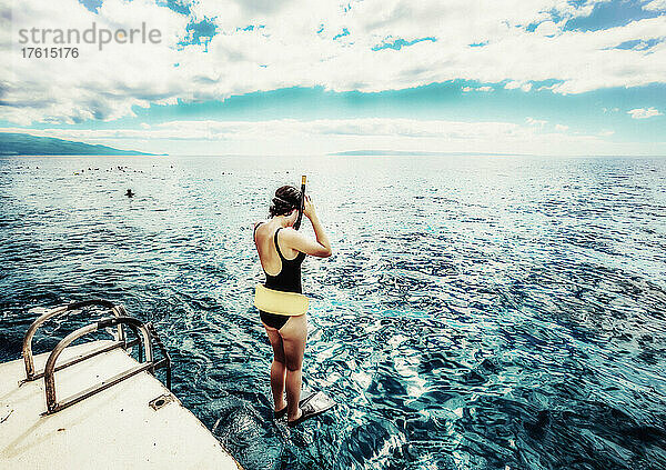 Frau  die von einem Boot mit Schnorchelausrüstung ins Wasser springt  um sich anderen Schnorchlern an der Küste von Maui anzuschließen; Maui  Hawaii  Vereinigte Staaten von Amerika