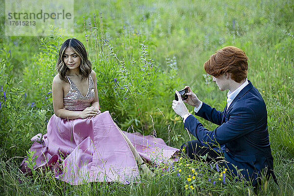 Junges Paar in formeller Kleidung bei der Aufnahme von Fotos auf einer Wiese in einem Park  Abschlussfoto-Shooting in Green Timbers Urban Forest; Surrey  British Columbia  Kanada