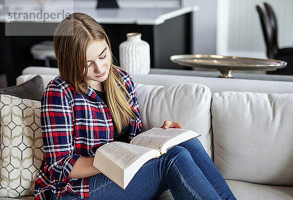 Teenager-Mädchen sitzt zu Hause auf einer Couch und liest in der Bibel; Edmonton  Alberta  Kanada
