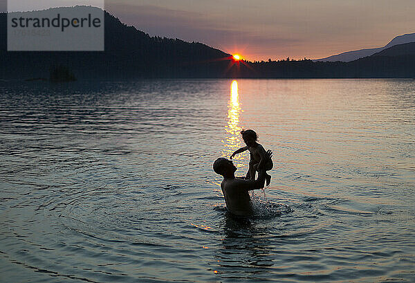 Vater und kleine Tochter spielen in einem See bei Sonnenuntergang  Ruby Lake an der Sunshine Coast von BC  Kanada; British Columbia  Kanada