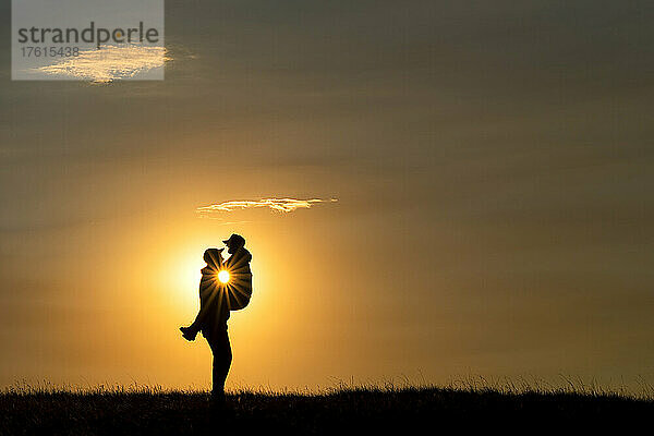 Silhouette eines verliebten Paares  während die Sonne hinter ihnen untergeht  Grasslands National Park; Val Marie  Saskatchewan  Kanada