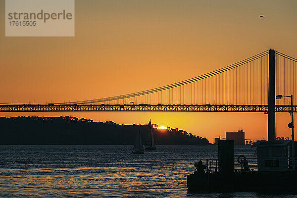 Silhouette der Brücke 25 de Abril über den Tejo  die Lissabon und Almada bei Sonnenuntergang verbindet; Lissabon  Estremadura  Portugal