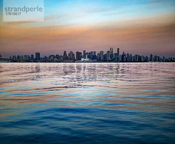 Blick auf die Skyline der Innenstadt von Vancouver und das Hafenviertel mit den Farben des Sonnenaufgangs  die sich im Wasser des Burrard Inlet spiegeln; Vancouver  British Columbia  Kanada