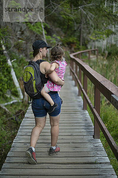 Eine Mutter trägt ihre kleine Tochter auf einem Wanderweg im Smuggler Cove Marine Provincial Park an der Sunshine Coast von BC  Kanada; British Columbia  Kanada
